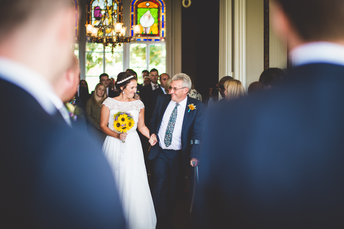 A wedding photographer captures the bride walking down the aisle with her father.