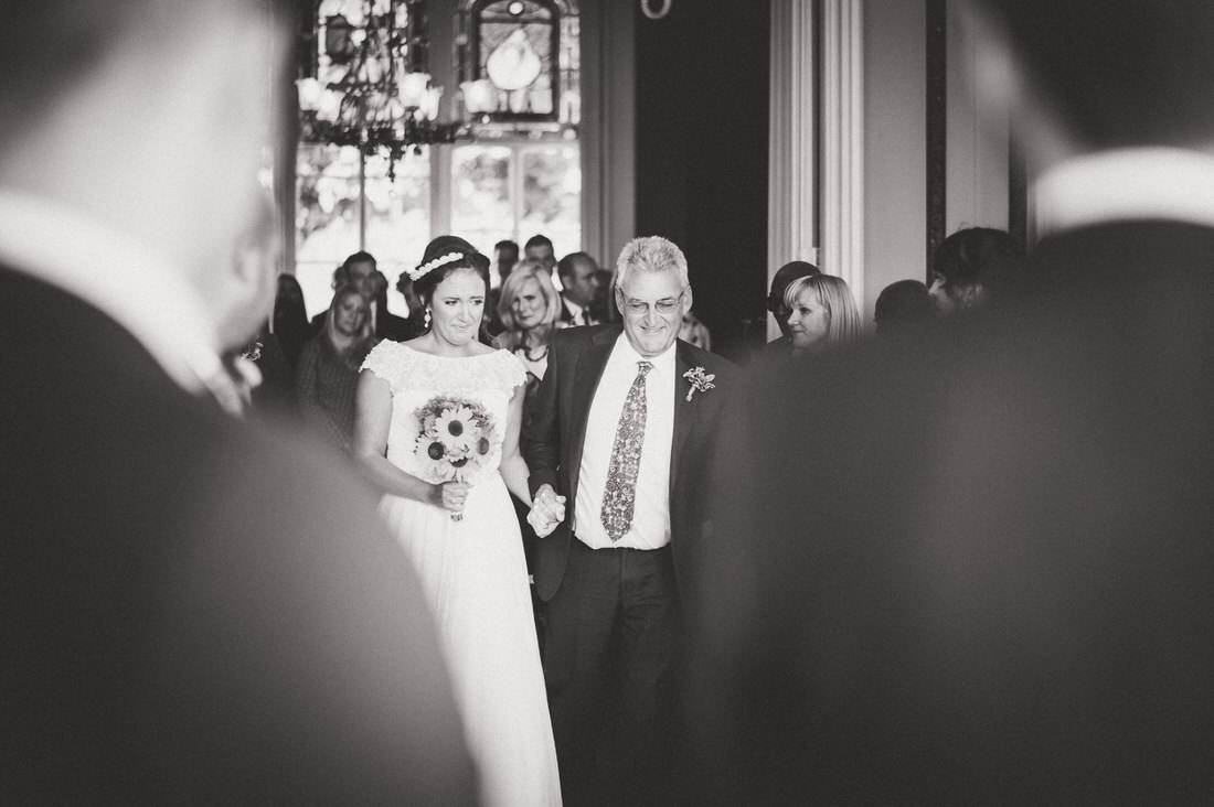 A bride walking down the aisle with her father captured by a wedding photographer.