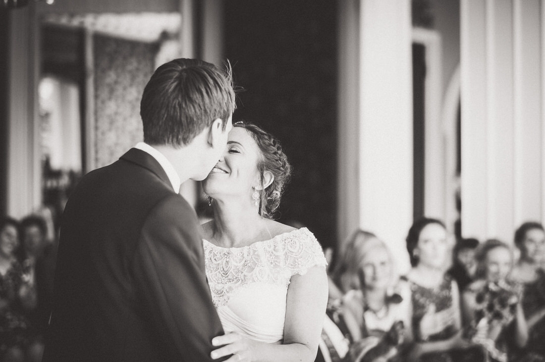 A groom kisses his bride in a beautiful wedding photo.