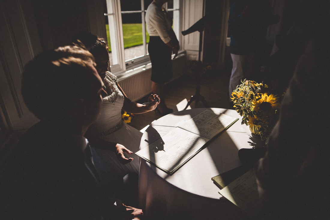 A bride and wedding photographer seated at a table in front of a window.