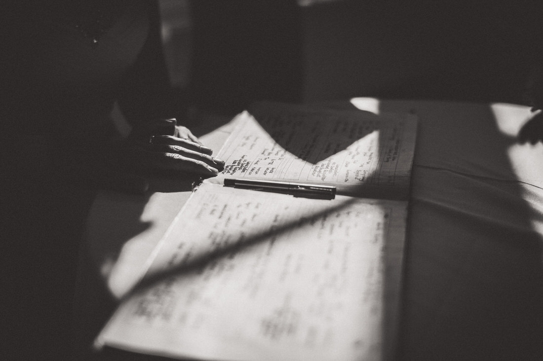 A groom writing on a piece of paper in front of a window.