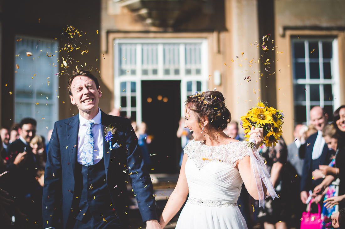 A wedding photo capturing the bride and groom departing a venue amidst confetti.