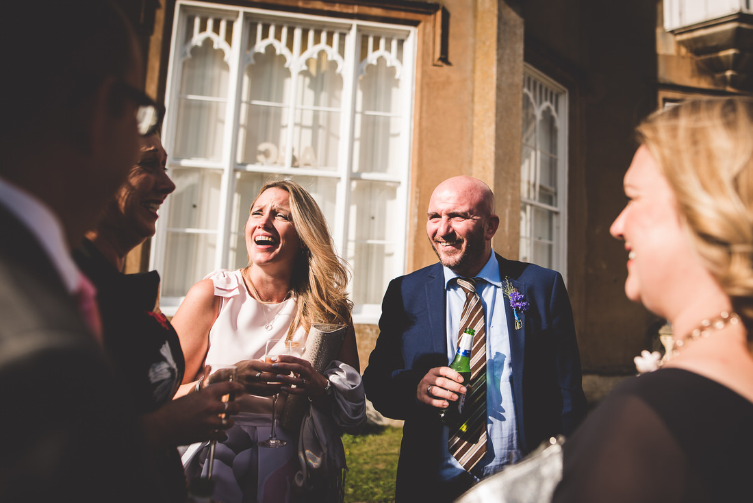 A group of wedding guests laughing in front of a building.