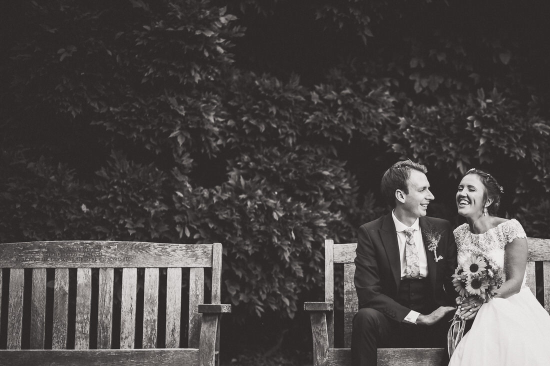 Wedding photo featuring a bride and groom on a bench.