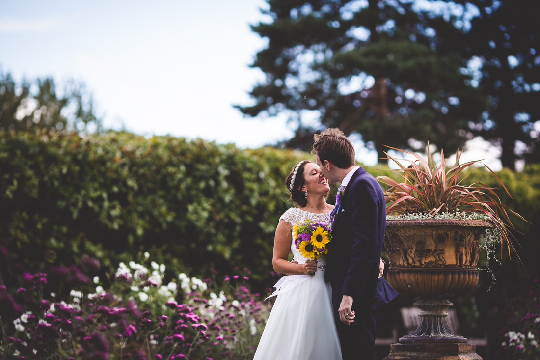 A groom kissing his bride captured by a wedding photographer in a garden.
