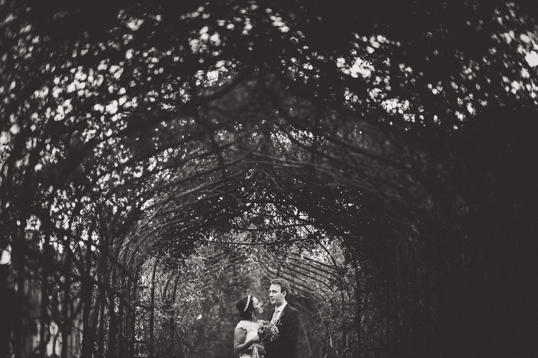 A monochrome wedding photo of a bride and groom in a tunnel.