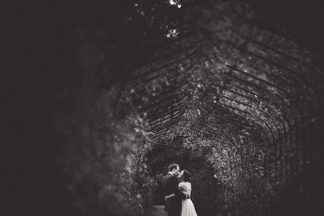 Black and white wedding photo of bride and groom in a tunnel.