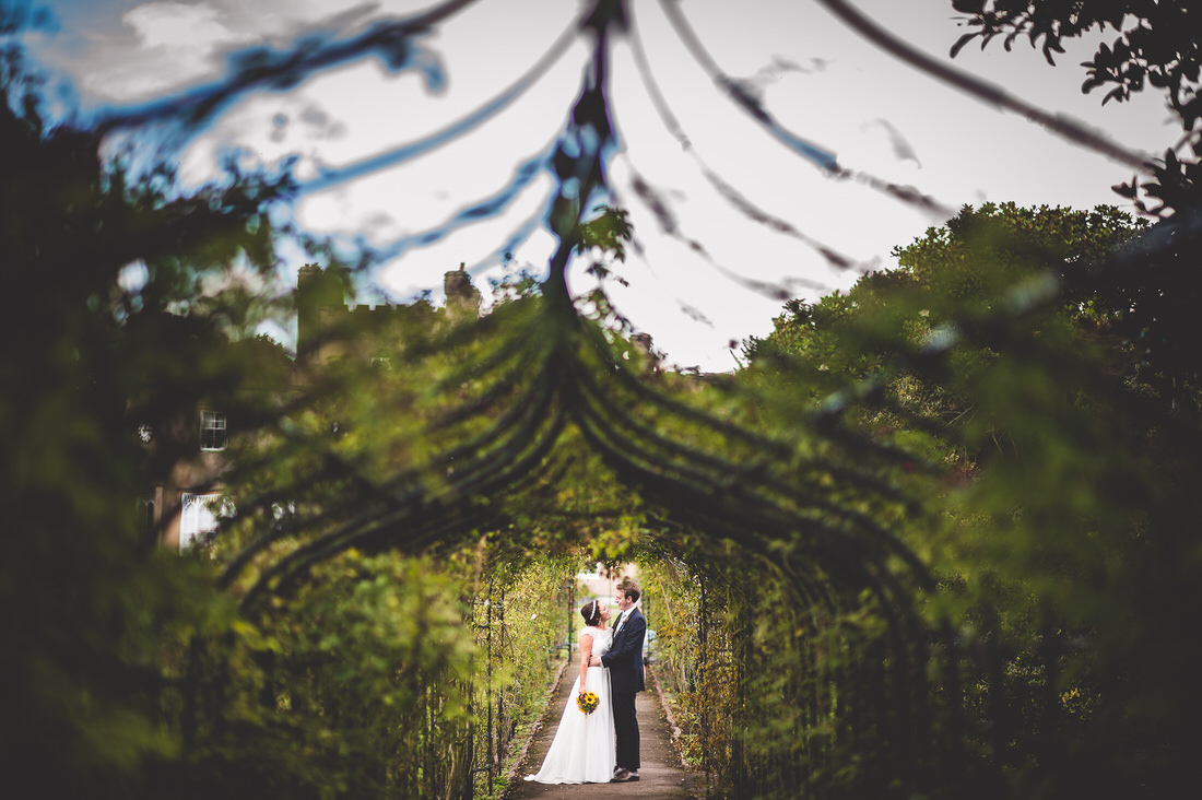 A groom and bride captured in a romantic garden setting by a wedding photographer.