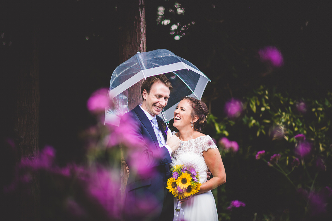 A groom under an umbrella in a wedding photo.