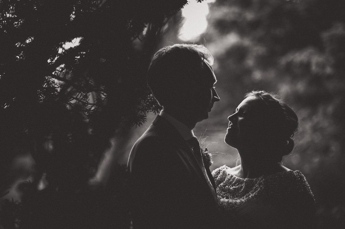 A wedding photographer captures a black and white silhouette of the bride and groom.