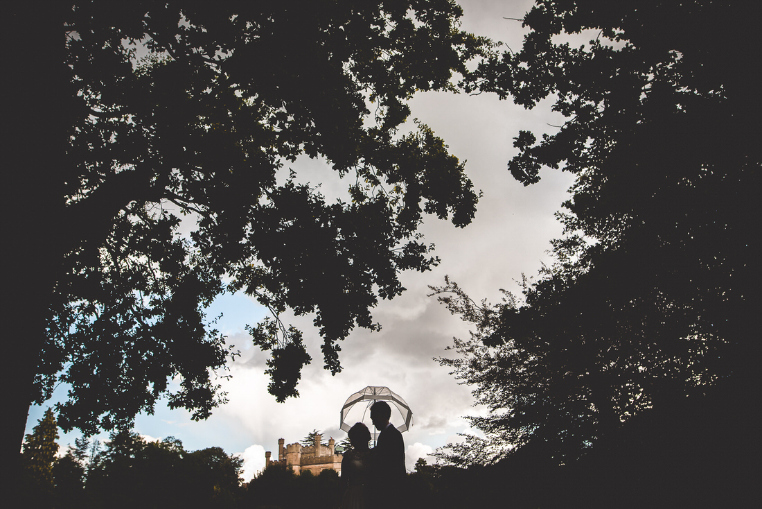 A wedding photo of a bride and groom standing under a tree.