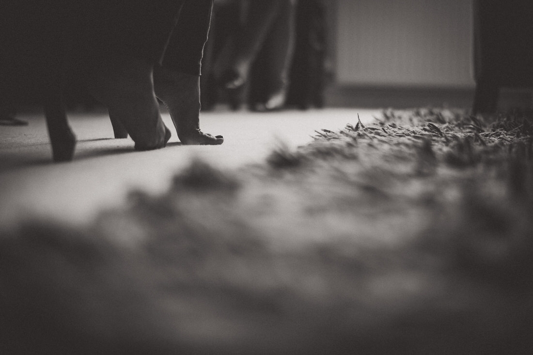 A black and white wedding photo featuring a woman's feet elegantly placed on a rug.