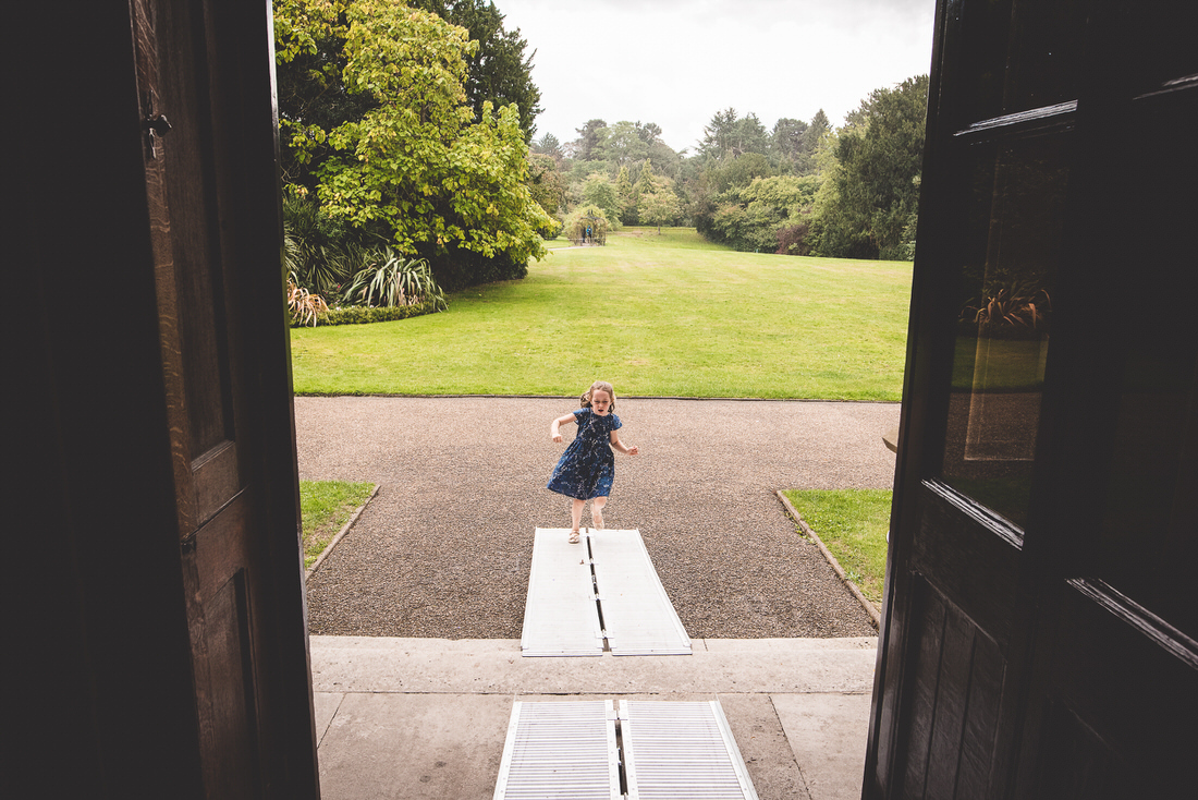A wedding photographer captures a girl standing in an open doorway for a wedding photo.