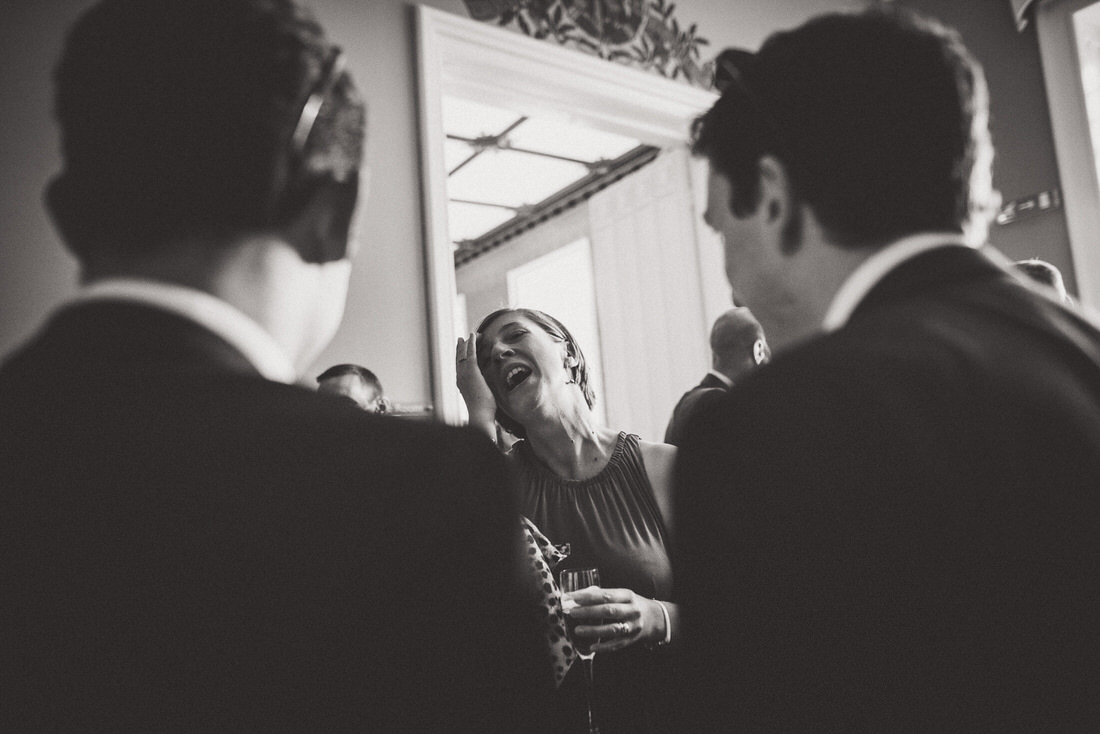 A black and white photo of a group of people laughing at a wedding.