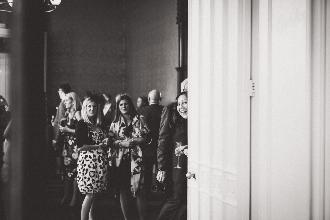 A black and white wedding photo capturing a group of people in a room.