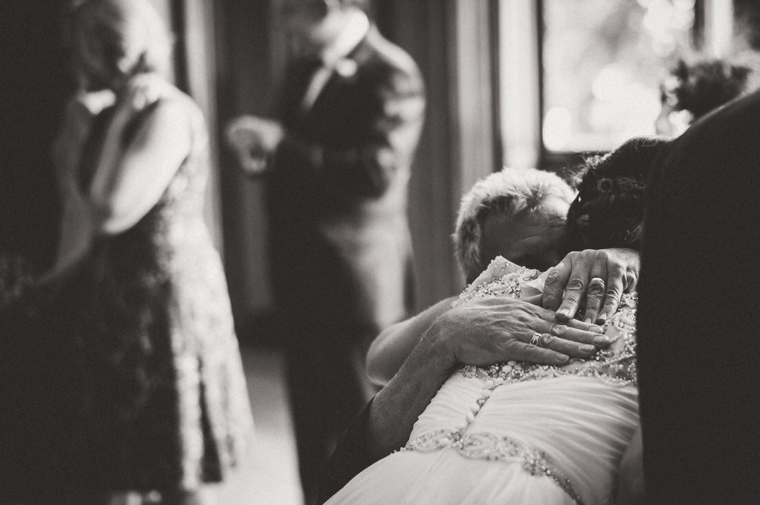 A bride hugging her mother during the wedding ceremony captured by a wedding photographer.