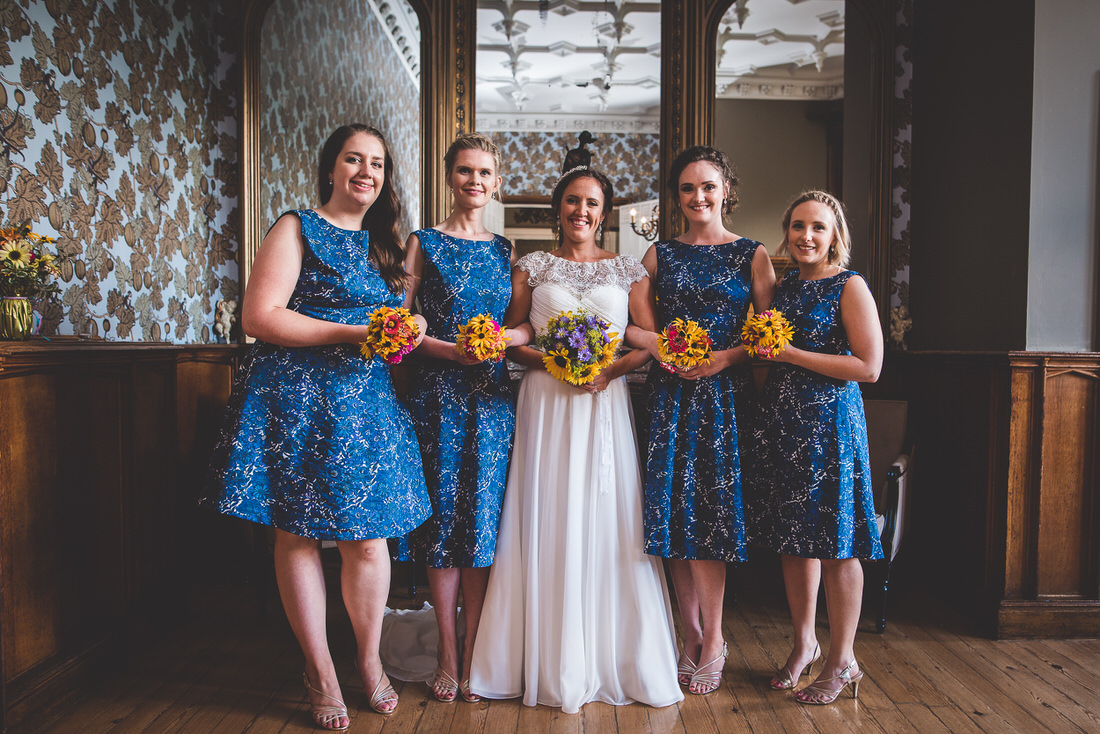 A wedding photo featuring the bride and her bridesmaids in blue dresses.
