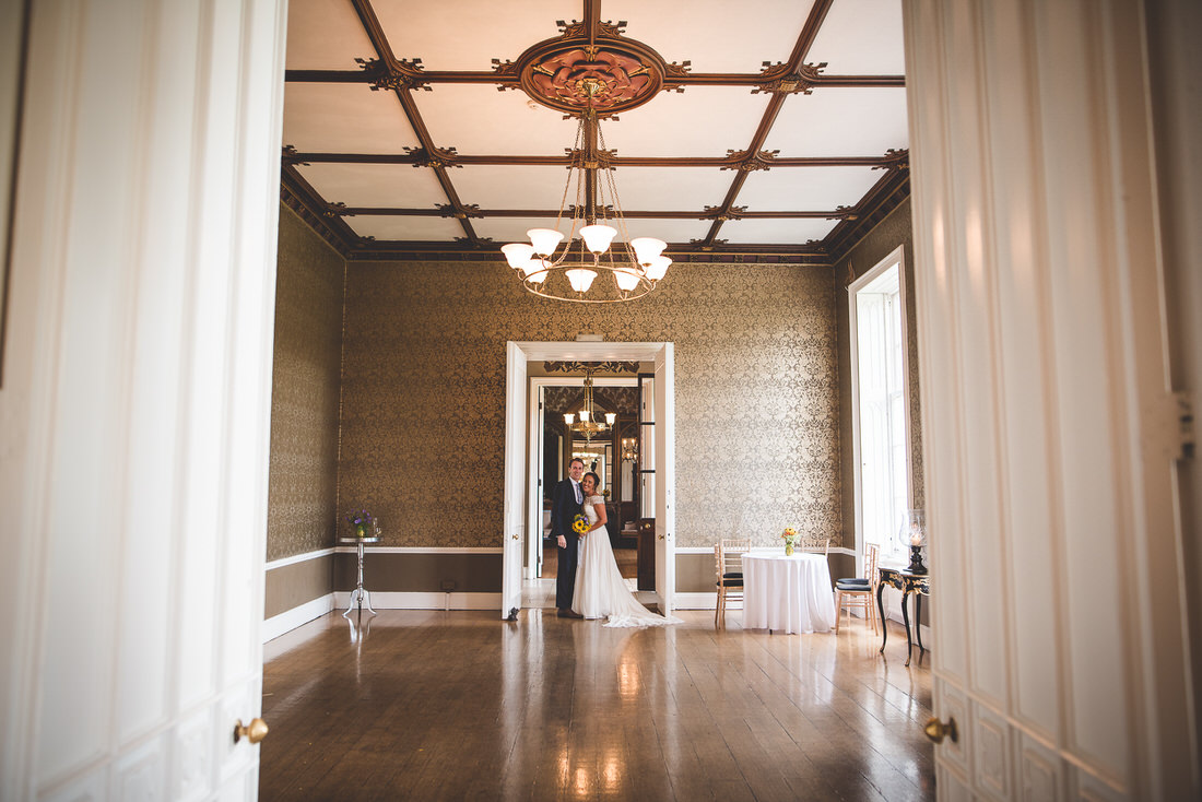 A wedding photo of a bride and groom in an ornate room.