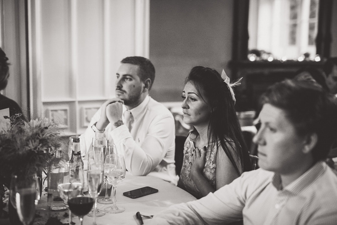A black and white photo of a wedding party sitting at a table.