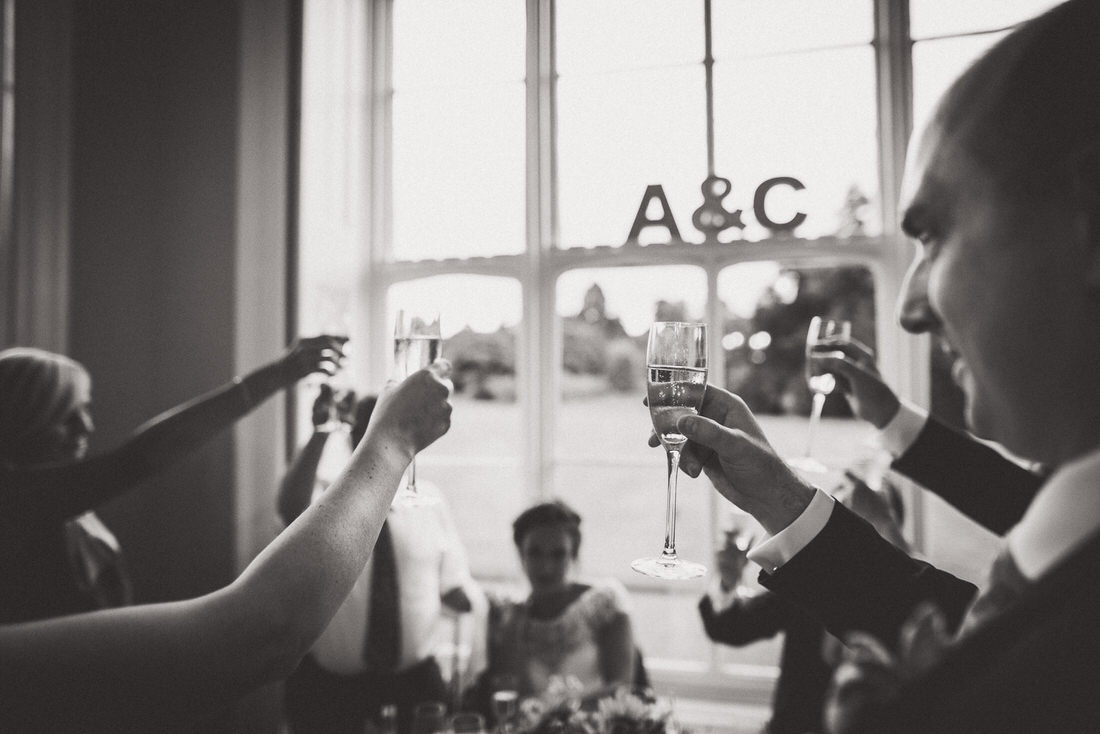 A black and white wedding photo capturing people toasting champagne.