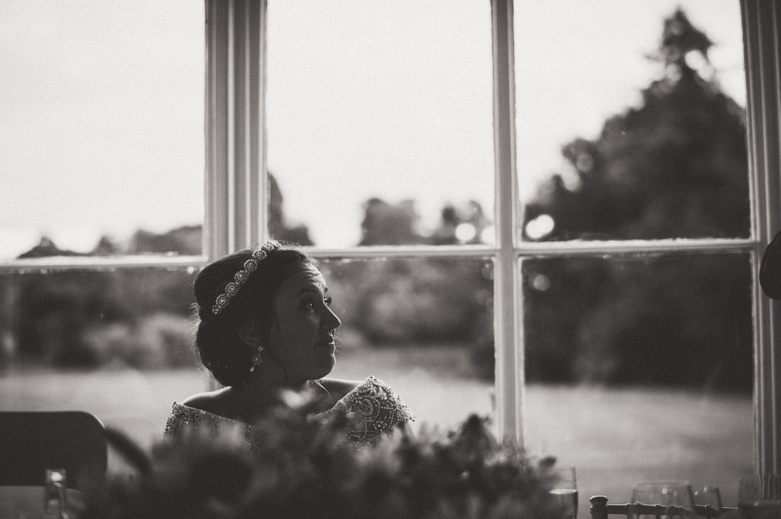 A bride poses for a wedding photo in front of a window.