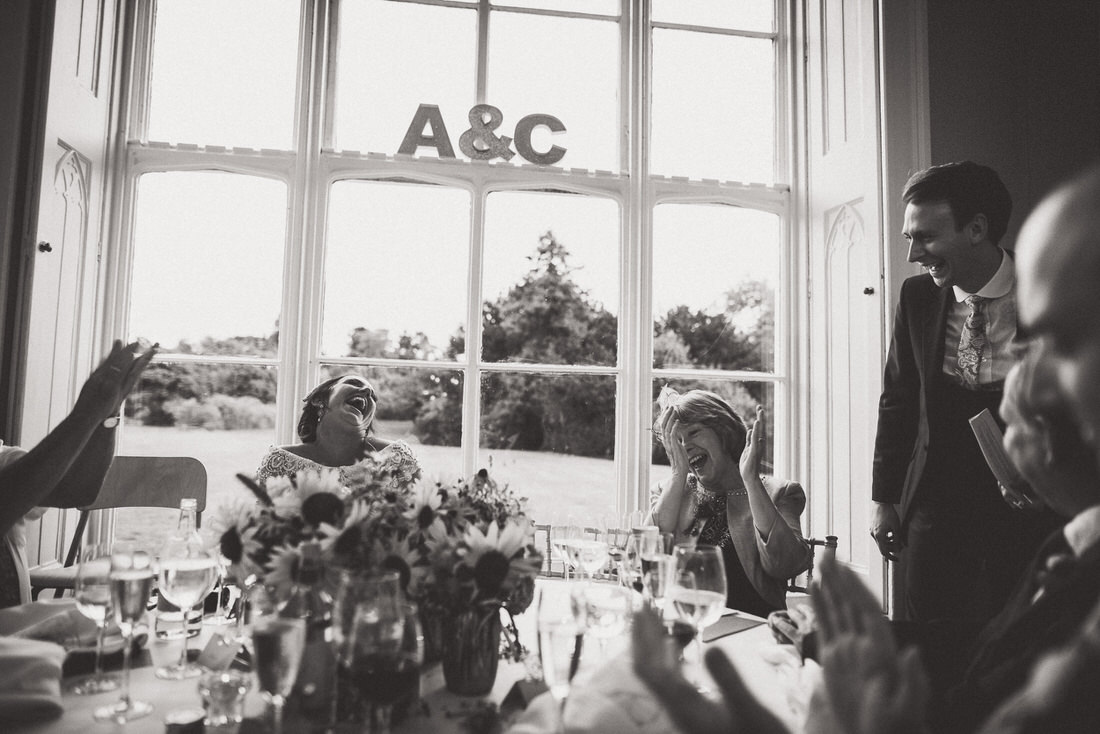 A black and white wedding photo featuring a clapping groom.