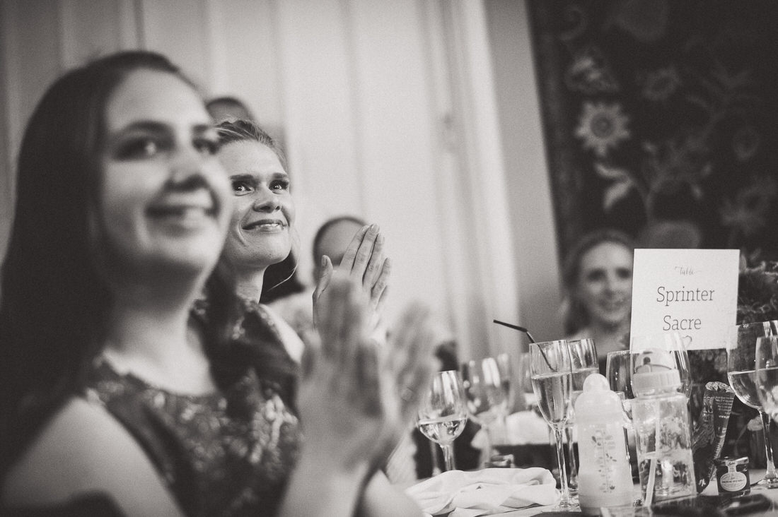 A wedding photo capturing guests joyfully clapping in black and white.