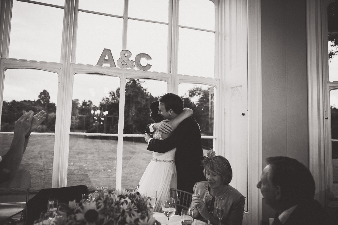 A bride and groom embracing in front of a window captured by a wedding photographer.