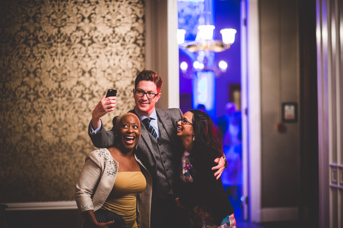 A group of people, including the bride, taking a wedding selfie in a room.