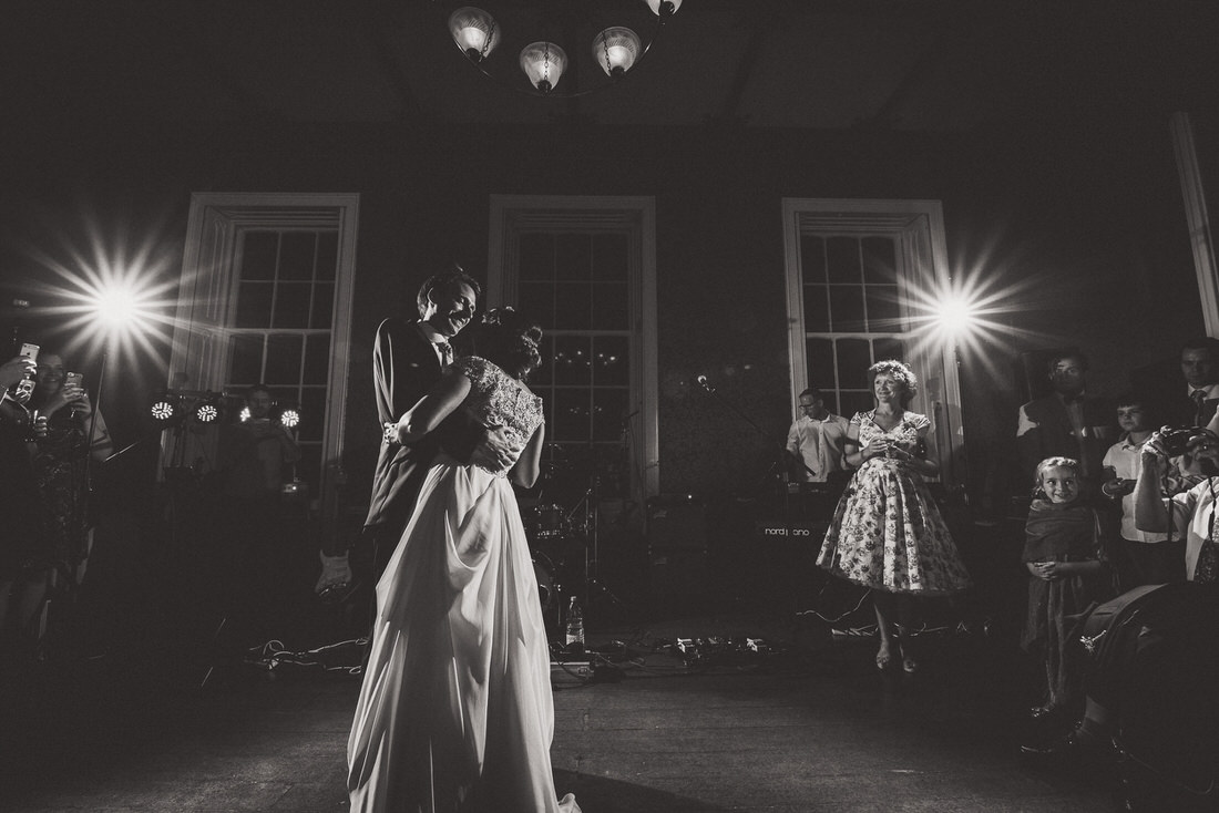 A couple's first dance captured by a wedding photographer in a dimly lit room.