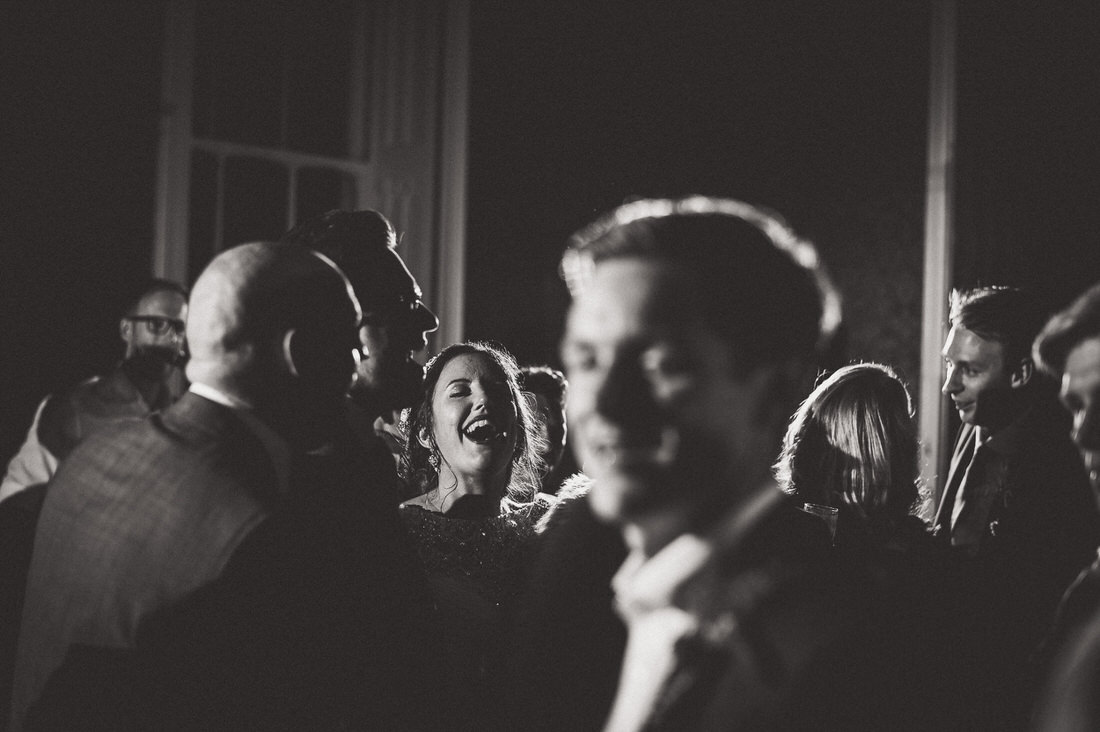 A black and white wedding photo capturing the bride, groom, and group of people.