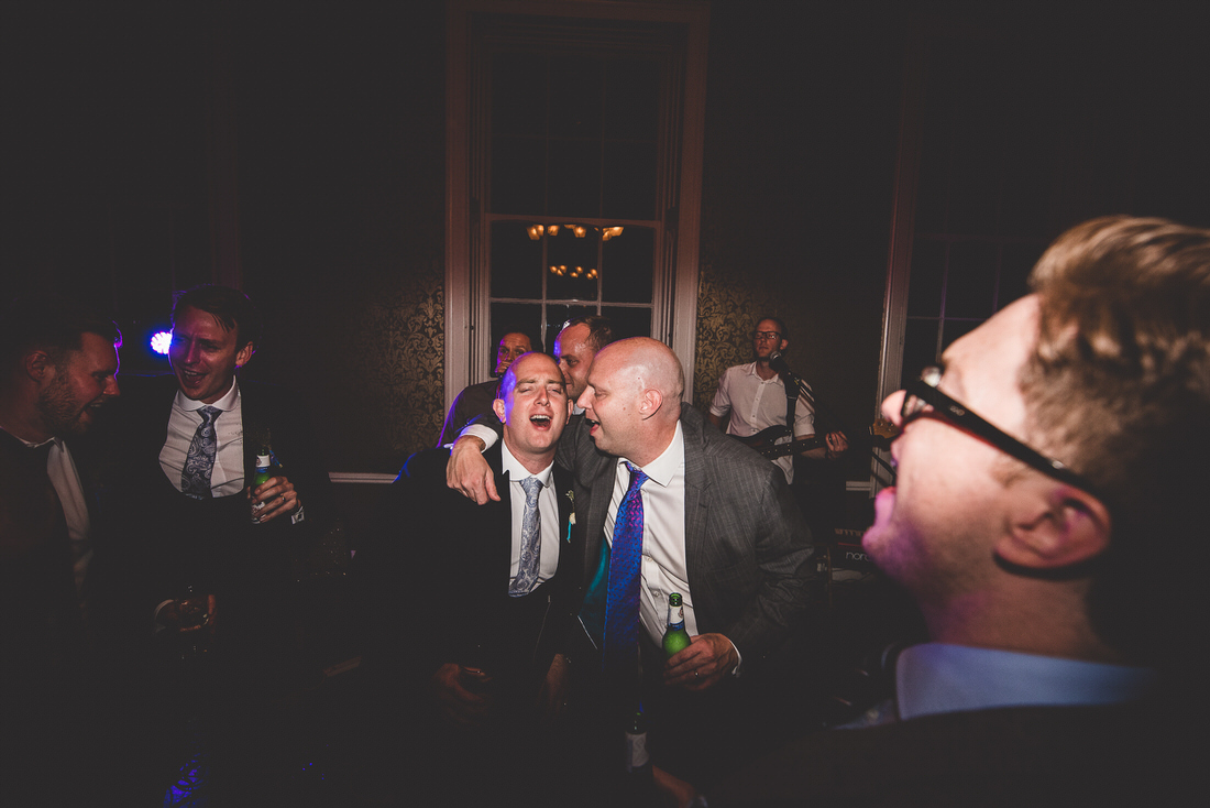 A group of men laughing at a wedding party.