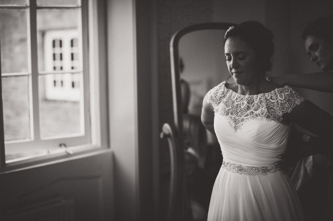 A bride preparing for her wedding ceremony in front of a window.