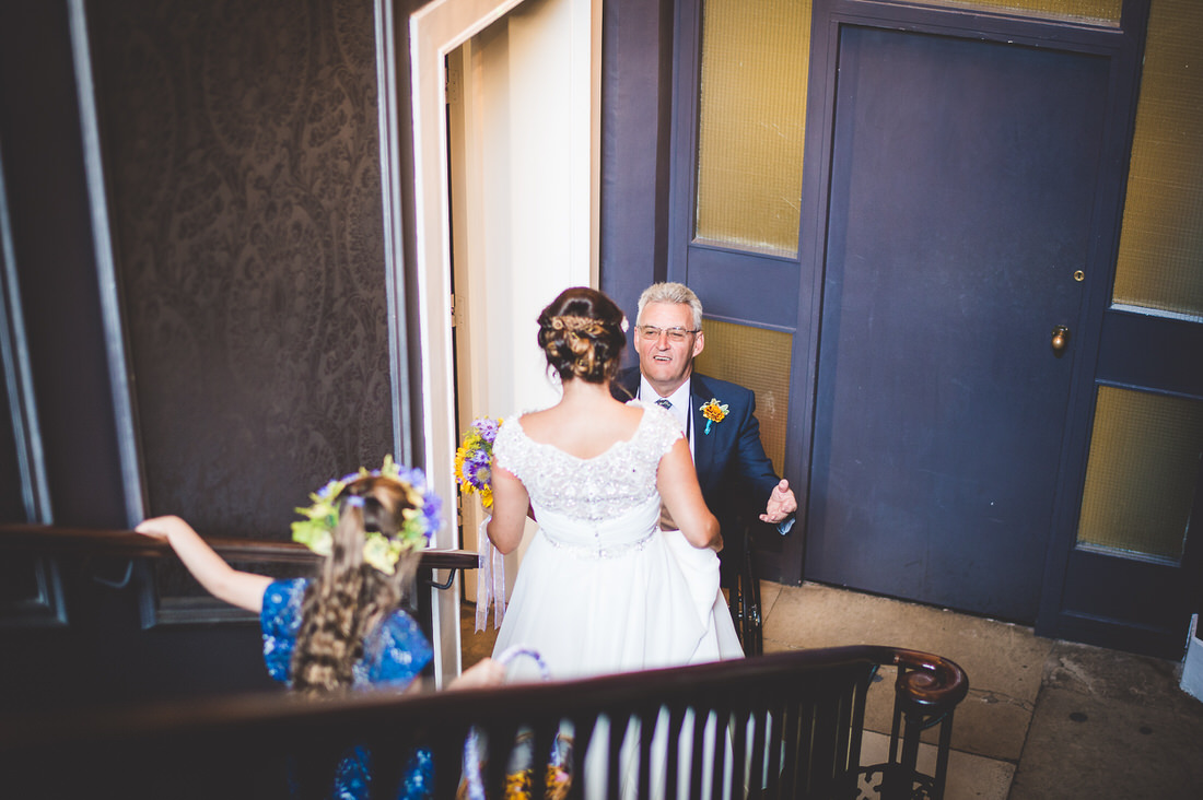 A bride is descending the stairs accompanied by her father during the wedding ceremony.