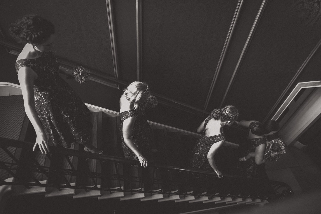 A wedding photographer captures a black and white photo of bridesmaids on the stairs.