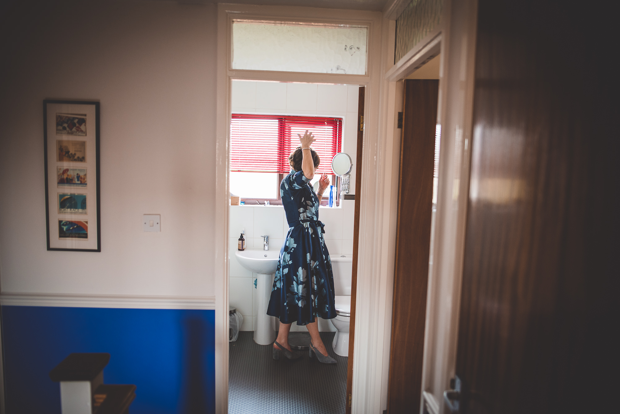 A bride in a dress standing in the doorway of a bathroom.