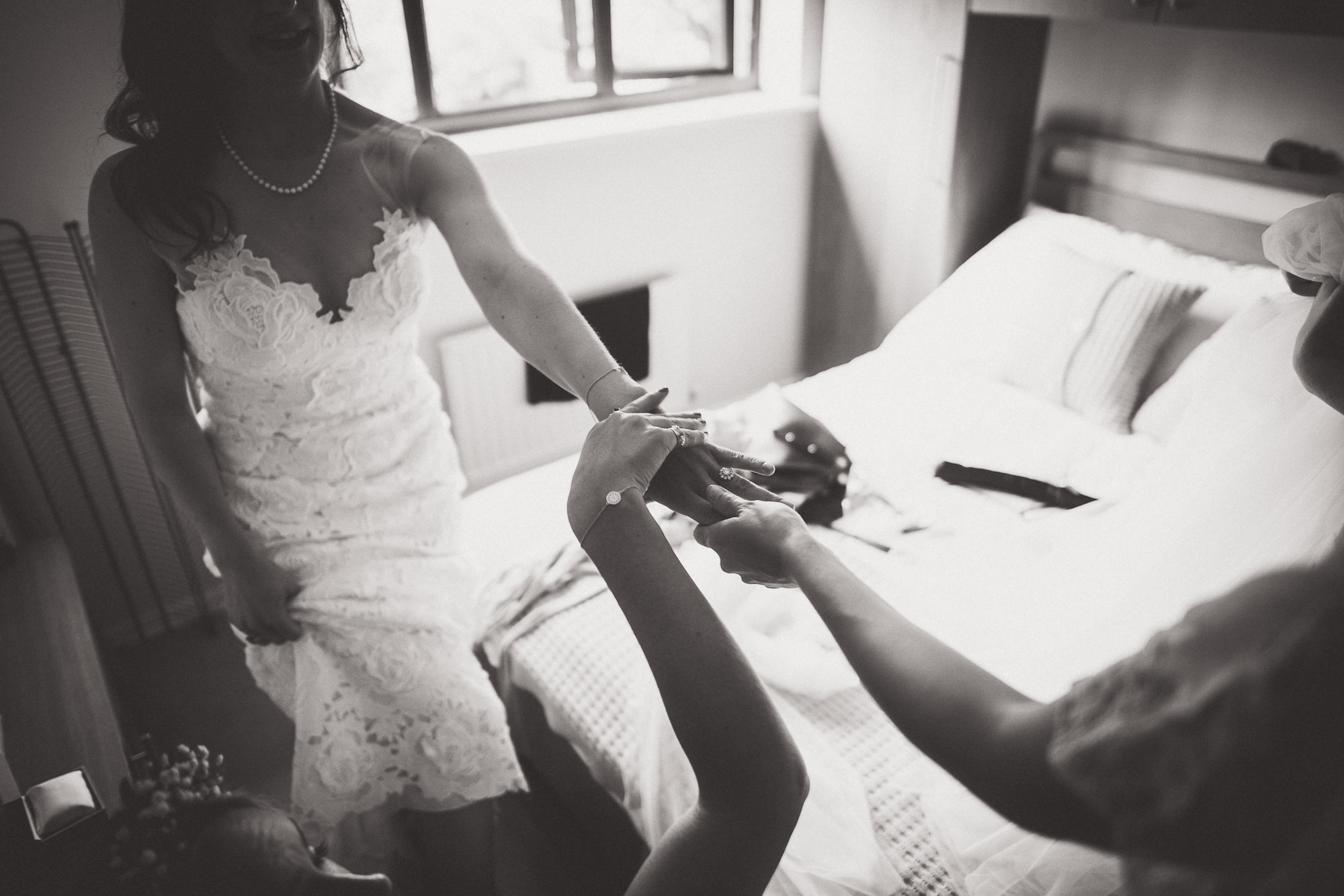 A bride and her bridesmaids prepare for wedding photos in a room.