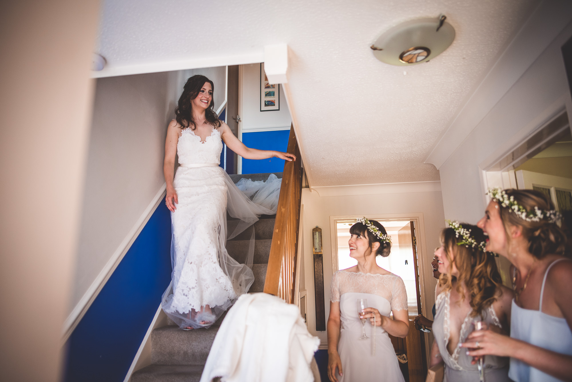 A wedding photographer captures the bride and her bridesmaids descending the stairs.