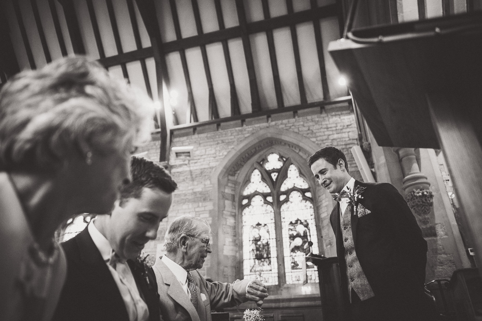 A wedding photographer captures a black and white photo of a bride and groom in a church.