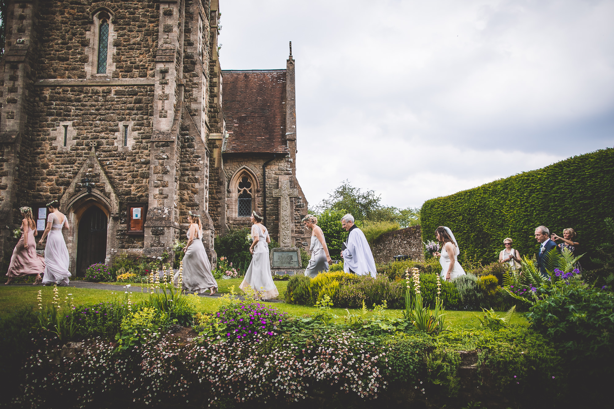A group of brides and grooms posing for a wedding photographer in front of a church.