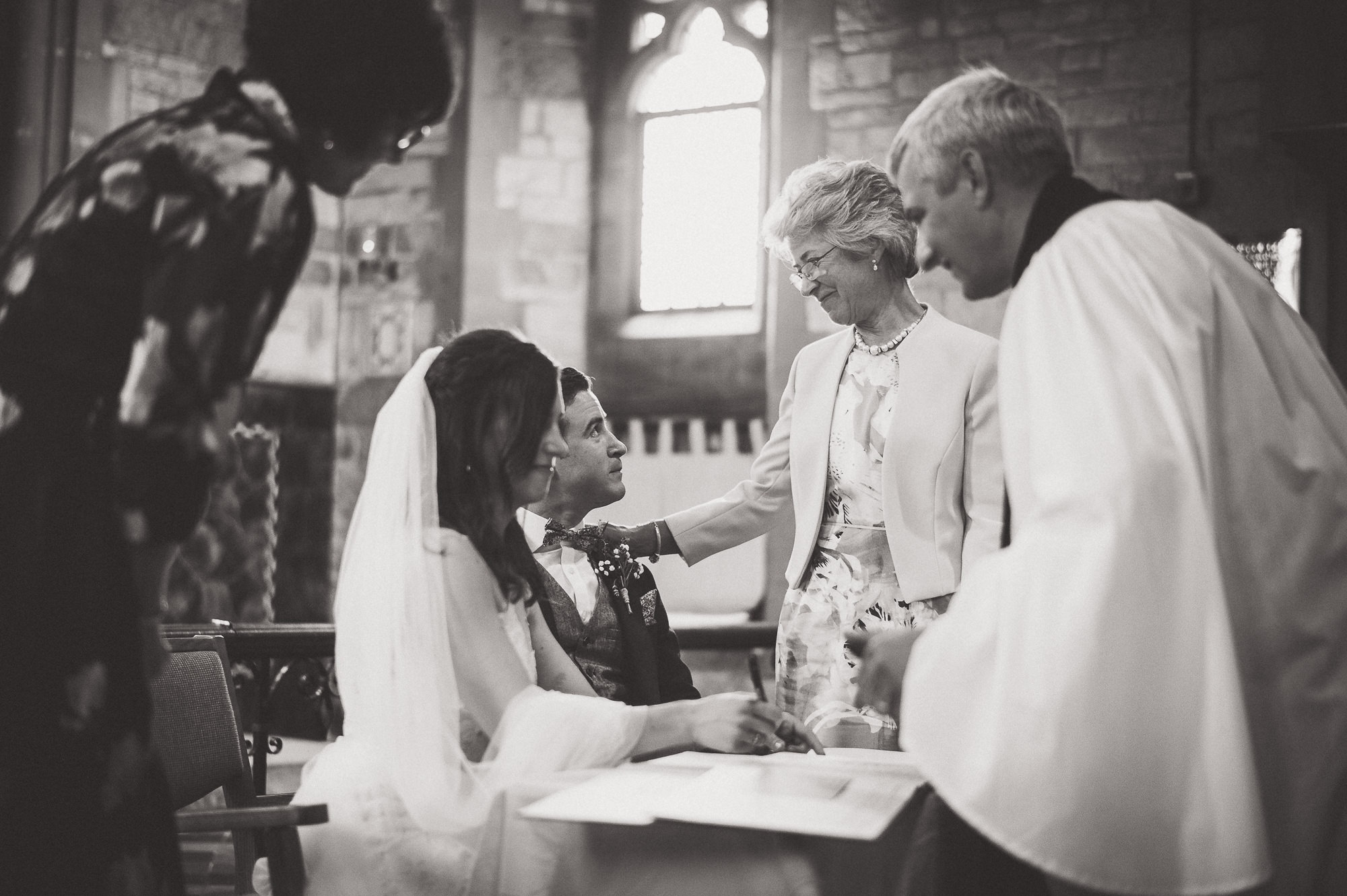 A wedding photographer captures a groom signing his wedding vows in a church.
