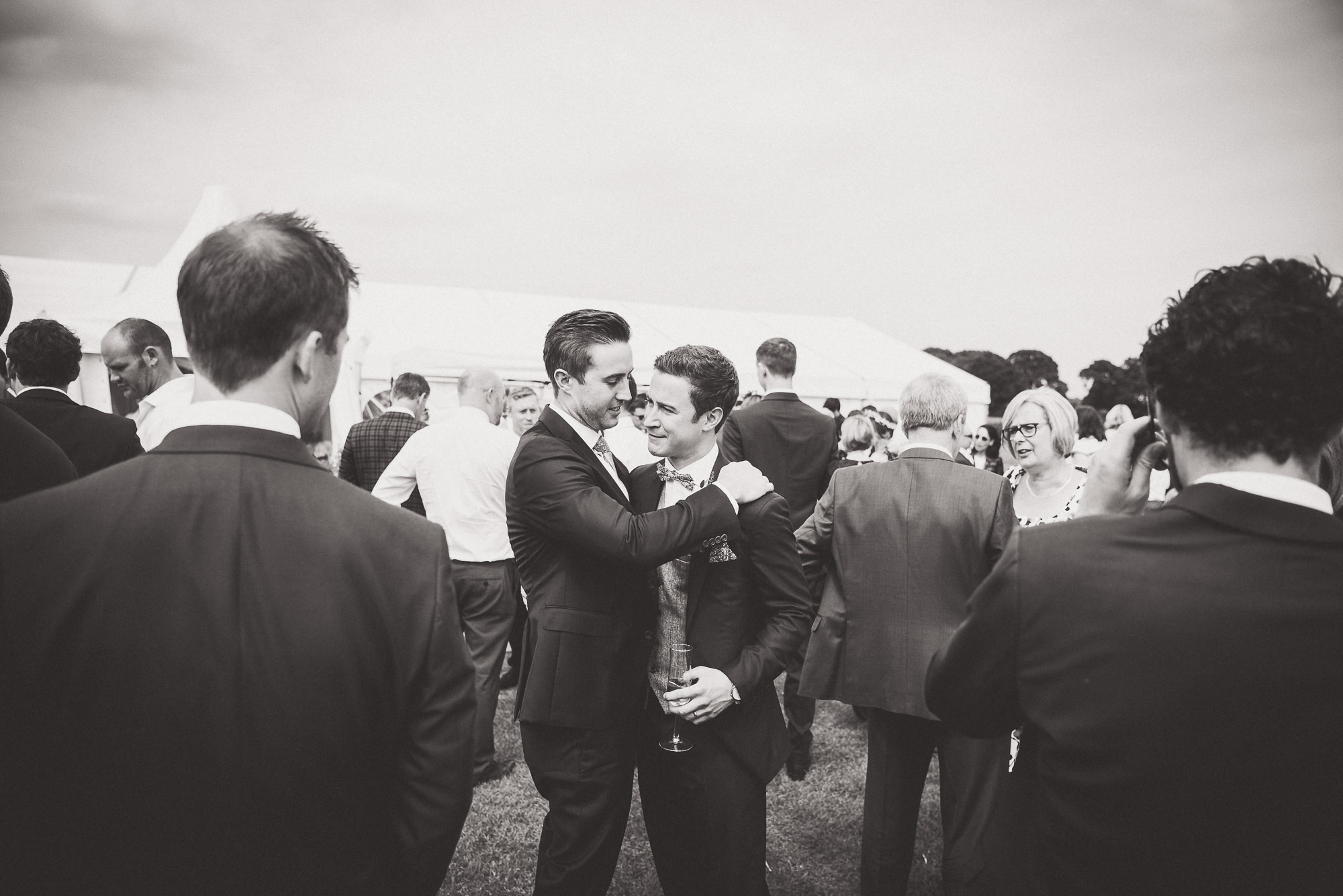 A black and white groom hugging his best man at a wedding.