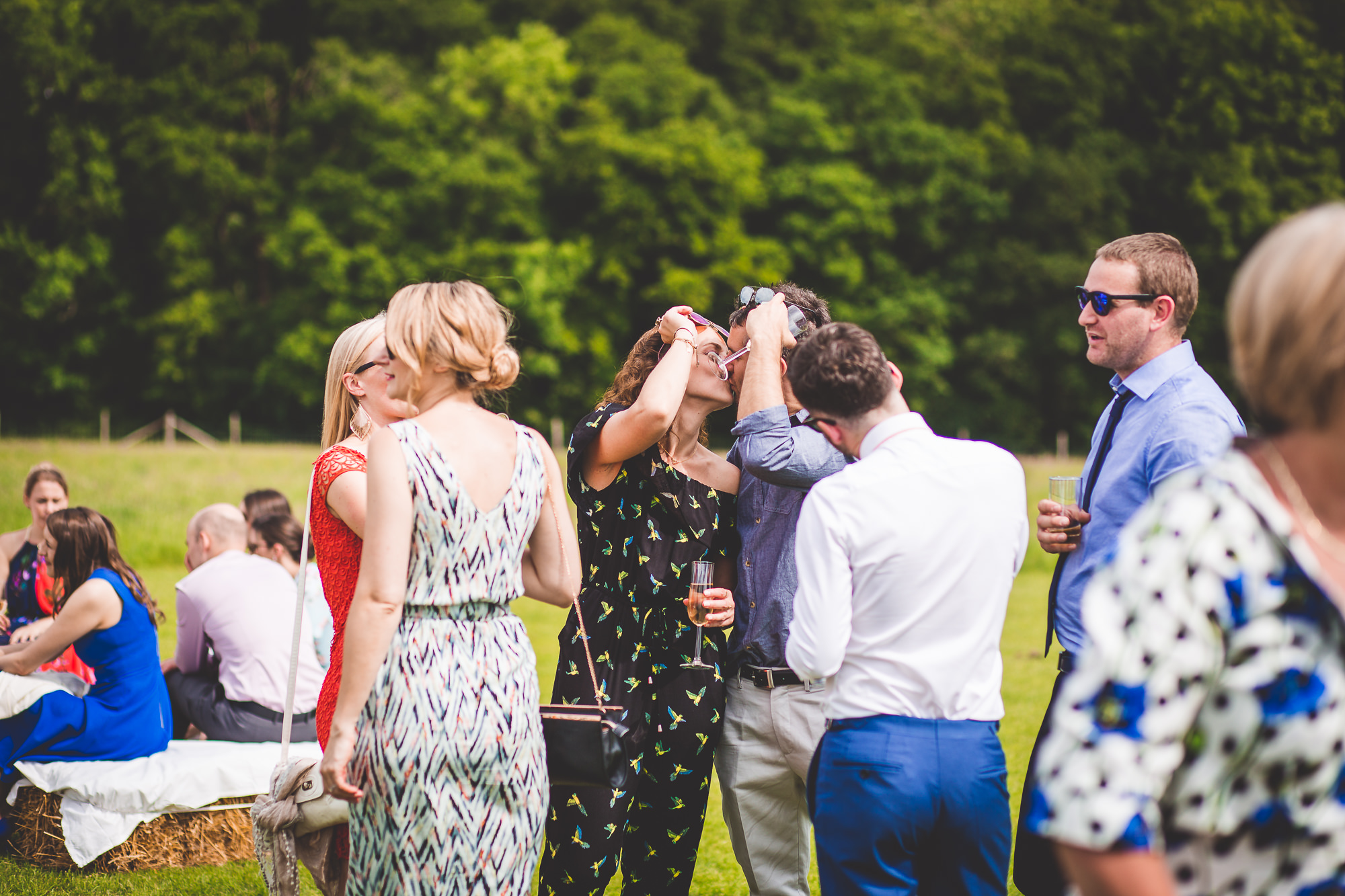 A wedding photographer captures the groom and his group of people gathering in a field.