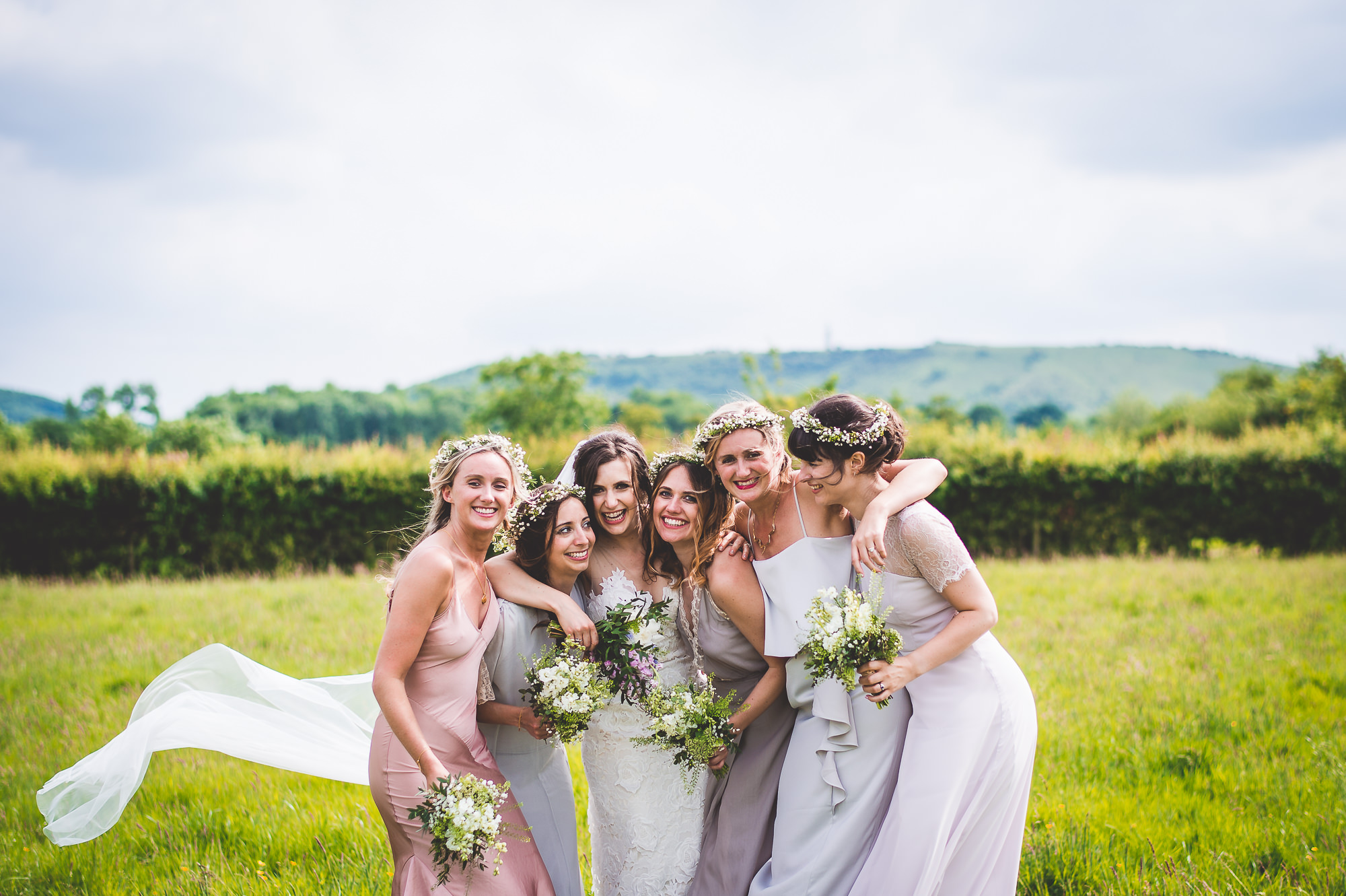 A group of bridesmaids posing for a wedding photo in a field.