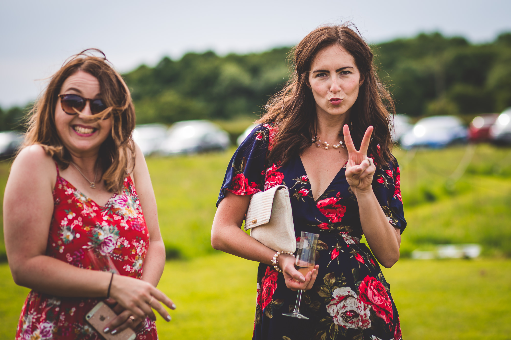 Two women in floral dresses posing for a wedding photo.