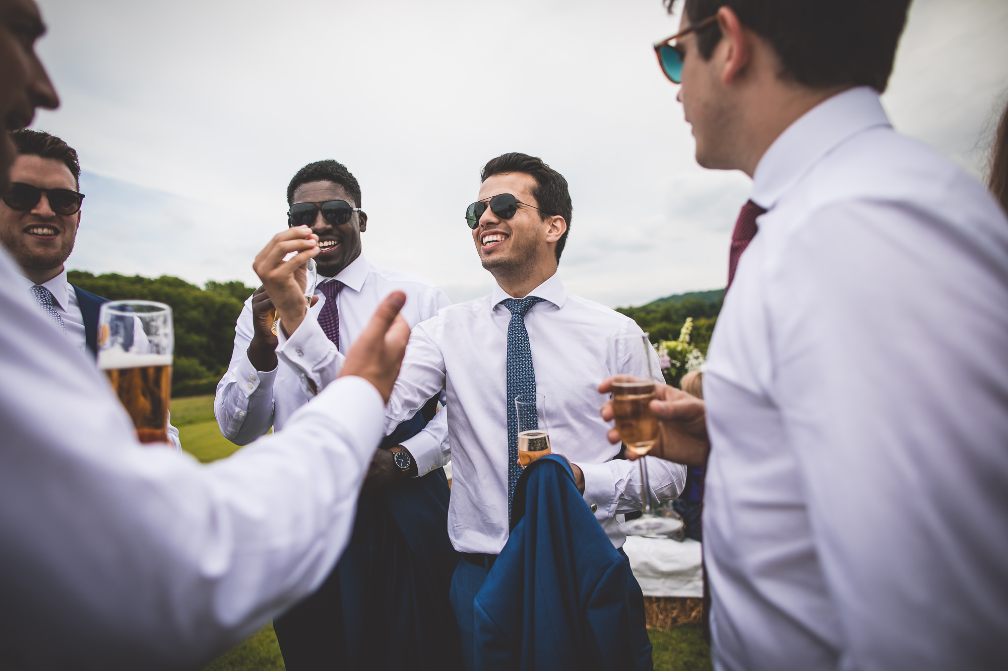 A group of groomsmen celebrating with beer at a wedding.