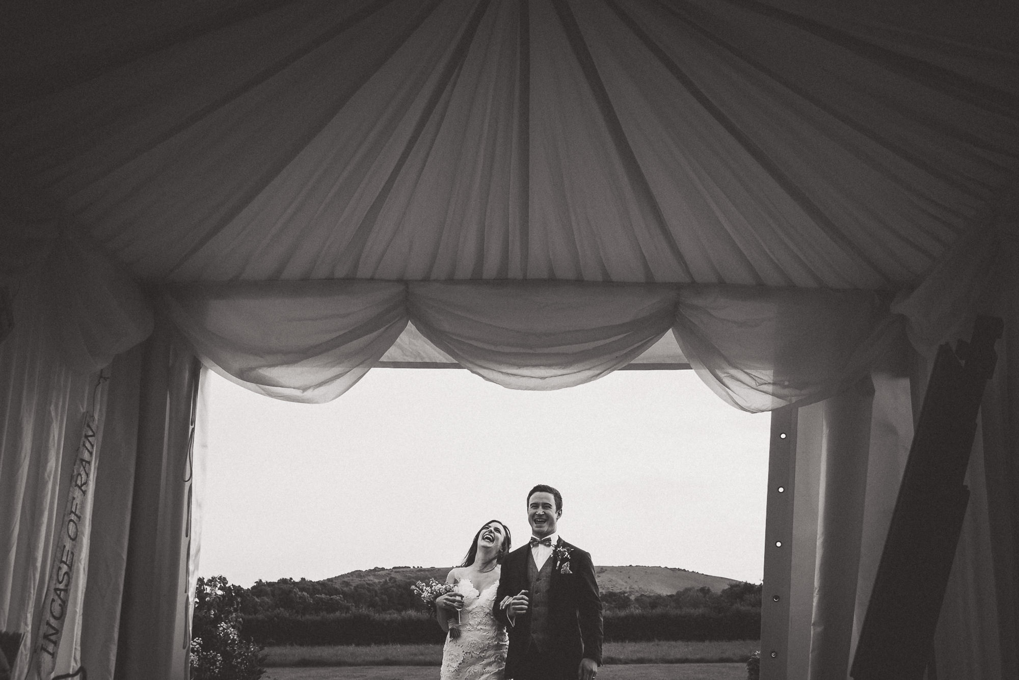 A wedding photo of a bride and groom in front of a tent captured by a wedding photographer.