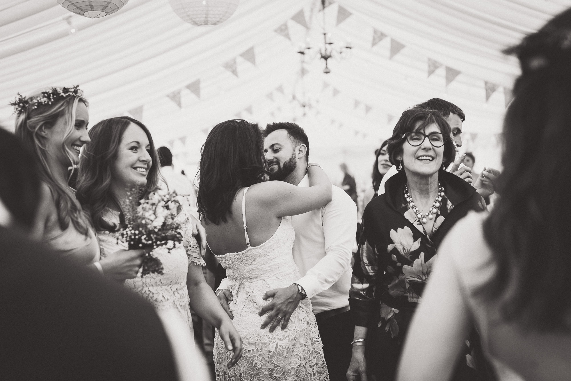 Black and white wedding photo capturing a bride and groom dancing under a tent.