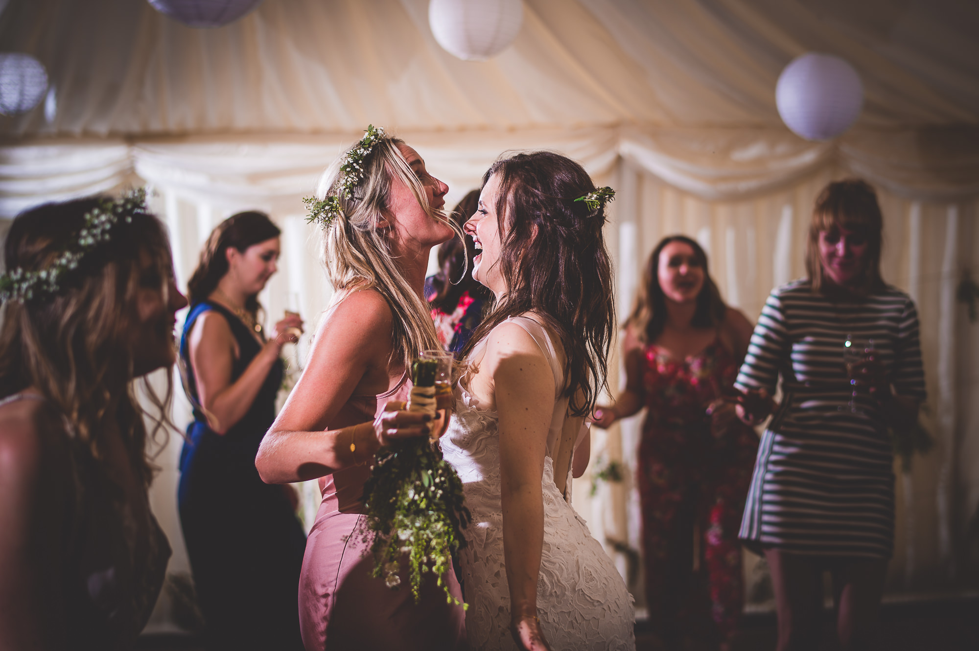 Wedding photographer captures two brides hugging on the dance floor in a heartwarming wedding photo.