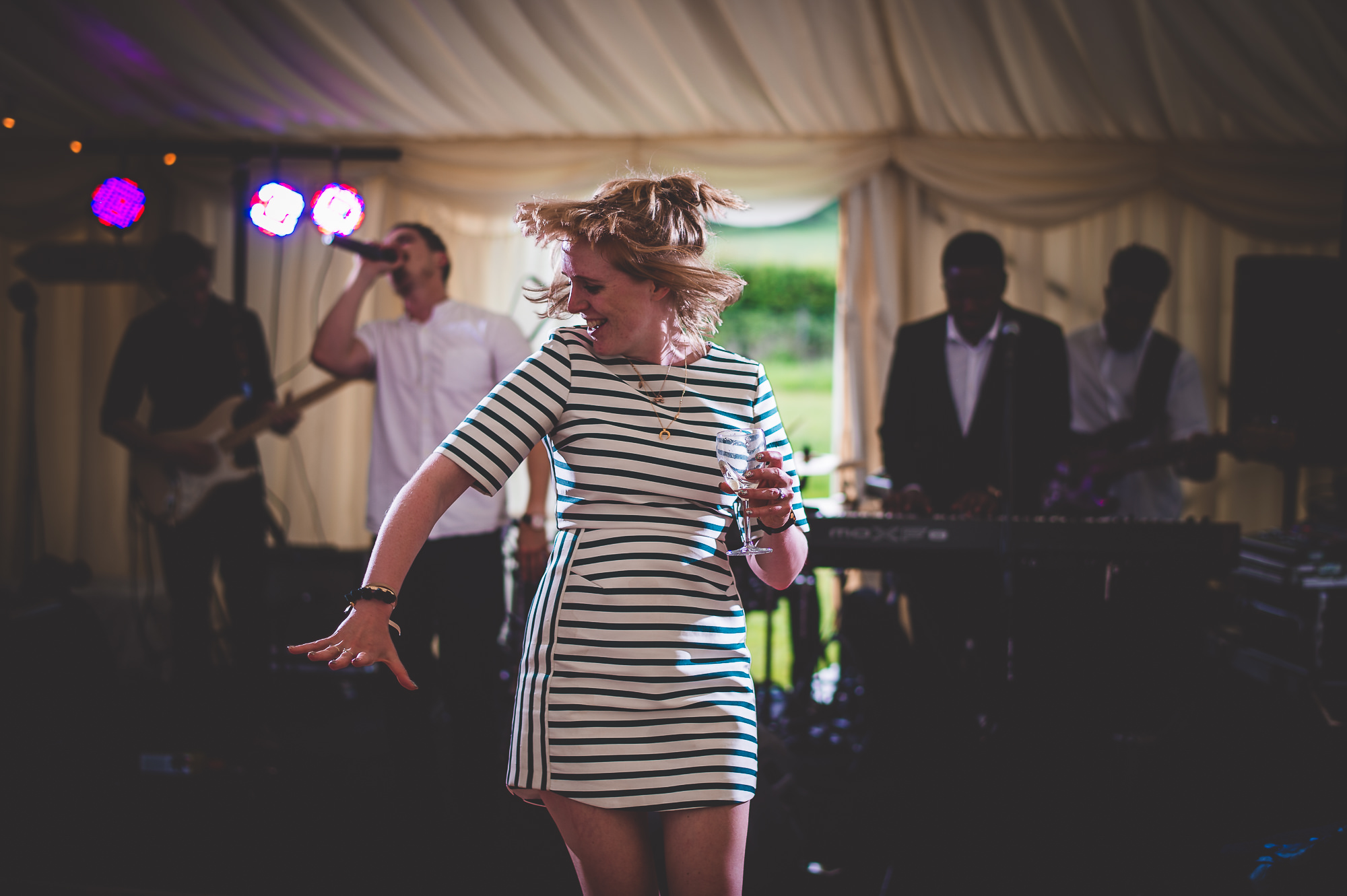 A bride dancing in a striped dress during her wedding reception.